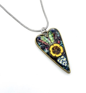 Close up of a Necklace with a chain and a long heart containing floral and leaf elements.