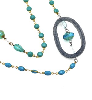 Close up of a Necklace with a beaded chain containing sections of blue beads and a large stone ring with blue beads through it.