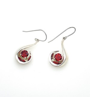 A pair of silver, scoop shaped earrings with a red gemstone.
