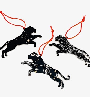 Three black tiger shaped ornaments cut from Circuit Board hung with orange string.
