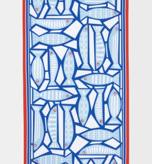 A table runner with a white background and blue fish arranged in a geometric pattern, there is a red frame around the edges.