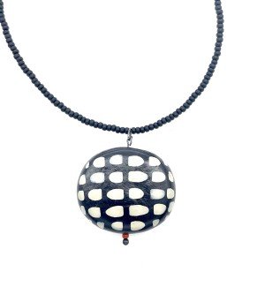 A black beaded necklace with a black pendant with white oval spots.