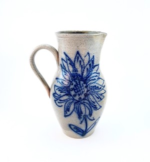 A white ceramic pitcher with a blue illustration of a sunflower on the front.