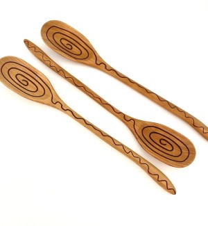 Three wooden spoons with a swirled pattern etched into the fronts.