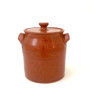 A lidded red ware jar with small handles on either side and a decorative finial on the lid.