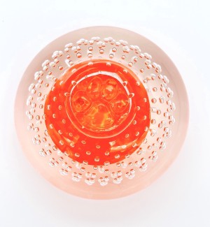 Handblown clear Glass orb with bubble pattern and orange glass inside with a paw stamped on top.