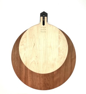 A set of two round cutting boards stacked on top of one another, the top one is a darker shade of wood.