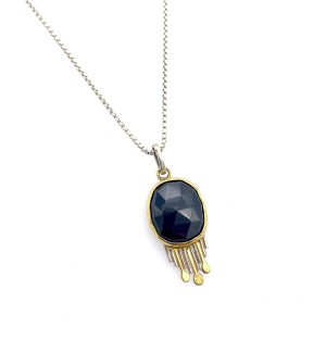 A pendant with a black faceted gemstone and small wires hanging down below.
