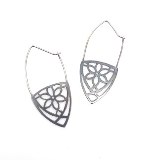 A pair of blackened earrings with a carved floral pattern.