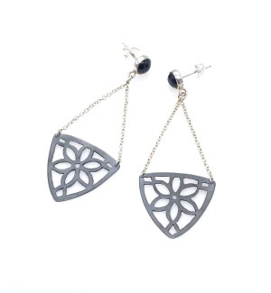 A pair of blackened earrings with a carved floral pattern hanging from a post with a black gemstone.