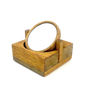 A small wooden block with two posts sticking up from either side to hold a rotating round mirror.