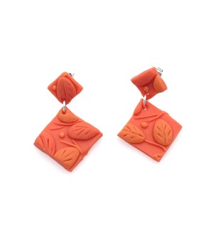 hand sculpted polymer clay dangle Earrings that are orange with sculpted leaves on them.