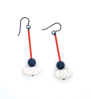 black wire drop earrings with line of red beads, a medium black round lava stone, and a larger textured white porcelain bead.