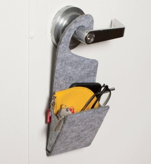 A felted pocket hanging from a doorknob holding keys and a wallet.