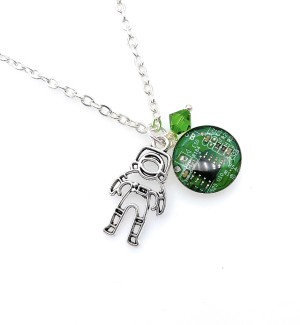 A green pendant with a circuit board design and silver astronaut charm and green diamond shaped bead on a silver chain.