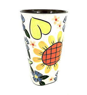 Ceramic Tumbler with a white background and a large flower with an orange center and yellow petals, above is a large green heart.