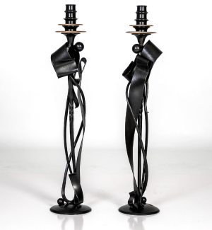 Tall black metal candlestick holders with a ribbon like pillar and two tiers of bronze wax catches.