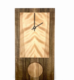 Rectangular clock with dark body and light face with short pendulum made from wood.