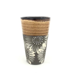 A tall ceramic tumbler with a brown tone body, accented with a ochre rim and a decorative illustration of sunflowers in white.
