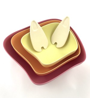 A set of organic shaped bowls nested with 2 serving pieces sitting inside, the largest is pink, the middle is orange, the smallest is yellow.