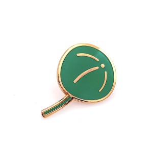 An enamel lapel pin in the shape of a pilea plant leaf in green enamel with gold outline.