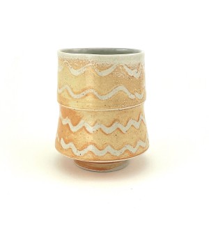 Ceramic tiered cup with wavy patterns of white on orange tone background with a green and interior.