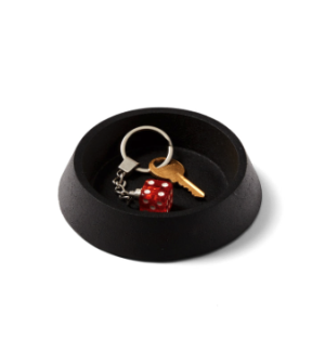 Round black cast iron tray with keys and red die.
