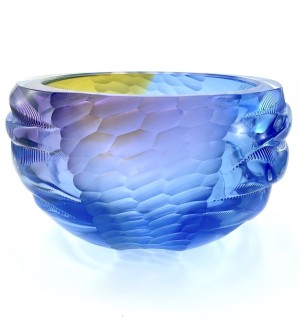 A luminous glass bowl with a carved, rippled and stamped textural surface in an aetherial icy blue, pale lavender and yellow gold color.