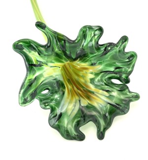 Glass flower that has a multi-colored throat and a full emerald green colored petaled bloom with a long green stem.
