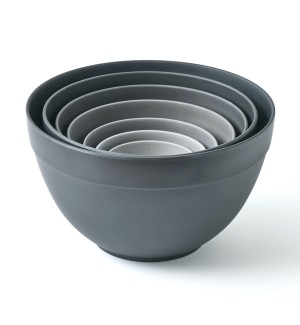 A set of 7 nested bowls in a geadation of greys, the largest bowl is the darkest grey, and the smallest is the lightest grey.