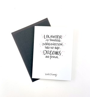 White paper greeting card with calligraphy 'Laughter is timeless Imagination has no age Dreams are forever' on cover. Dark grey envelope.