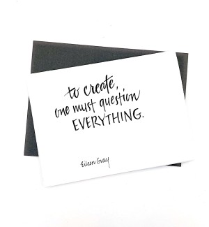 White paper greeting card with calligraphy 'to create, one must question EVERYTHING' on cover. Dark grey envelope.
