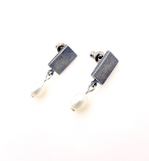 a pair of earrings with a rectangular hatch marked surface with a white pearl dangle.