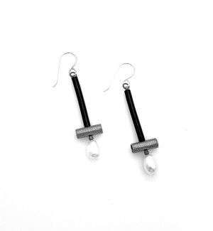 a pair of earrings with a black tube drop, a silver cross bar and white pearl drop.