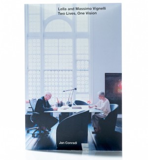 a book cover showing Lella and Massimo Vignelli working across from each other with the title 'Lella and Massimo Vignelli: Two Lives, One Vision' at the top in black font.