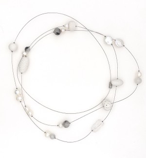 a necklace of a long thin cable that is strung randomly with beads in variety of shapes and materials including white porelain clay to white pearls to faceted glass.