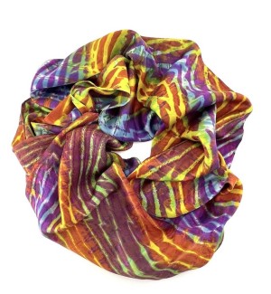 a silk scarf arranged in a circle that shows bold striations of color that include purple, blue, rose, gold.