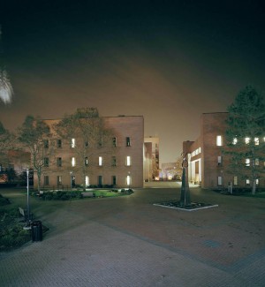 a hazy nightime color photgraph of a college campus quad with a surround of red brick buildings.