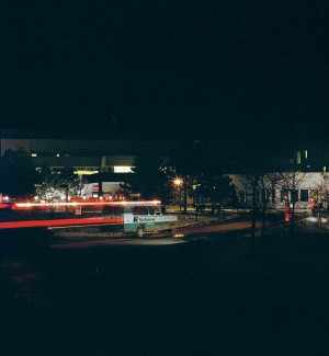 a panoramic color photograph of a nightime view of a building complex with an ambulance streaking past.