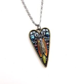 a heart shaped pendant with a cluster of beads and a beetle form encased in acrylic.