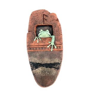 A hanging, oval shaped ceramic wall tile with a green frog head and arm sticking out.