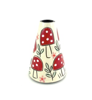 A cone shaped ceramic vase with a white background, hand illustrated red capped mushrooms with white dots and sprigs of green leaves.