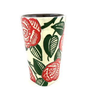 a ceramic tumbler with a white background and large red flowers and green leaves.