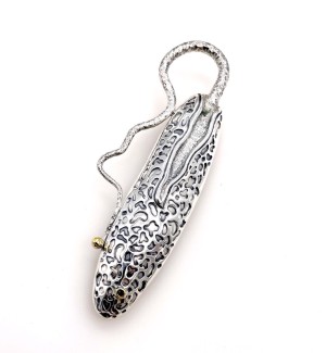 a long and narrow sterling silver brooch with a patterned surface with a tendril extending from the top along one side.