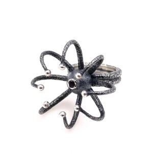 a sculptural ring with a protruding eight legged spider form with a ruby in the center.