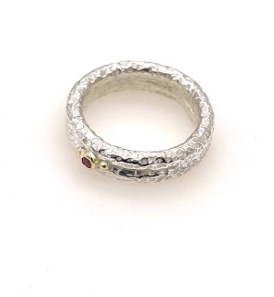 a silver textured double band ring with a ruby and a small gold ball on either side.