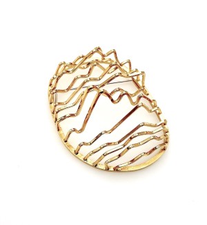 a golden brooch formed of narrow parallel bars bent in a zig zag shape with spaces between.
