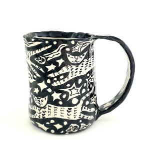 a ceramic mug with a textural surface and hand illustrated images of jumping cats and shooting stars.