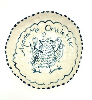 a hand formed ceramic bowl with hand ilustrated image of a dancing hen with words 'Madame Omelette'.
