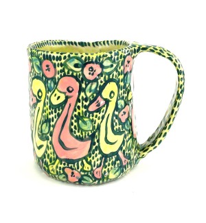 a hand formed ceramic mug with hand illustrated cartoonish ducks walking in a line with a green patterned background.